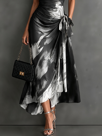 Vestido midi cruzado con estampado abstracto rojo y negro, cuello camisero en V, manga corta, lazo en la cintura y bajo asimétrico con volantes