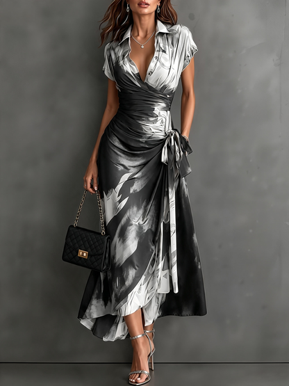 Vestido midi cruzado con estampado abstracto rojo y negro, cuello camisero en V, manga corta, lazo en la cintura y bajo asimétrico con volantes